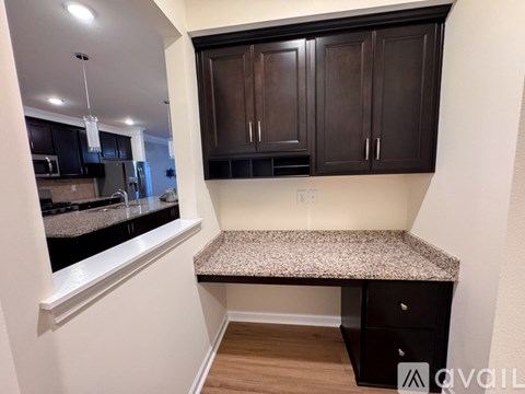 A kitchen with dark brown cabinets and a granite countertop.