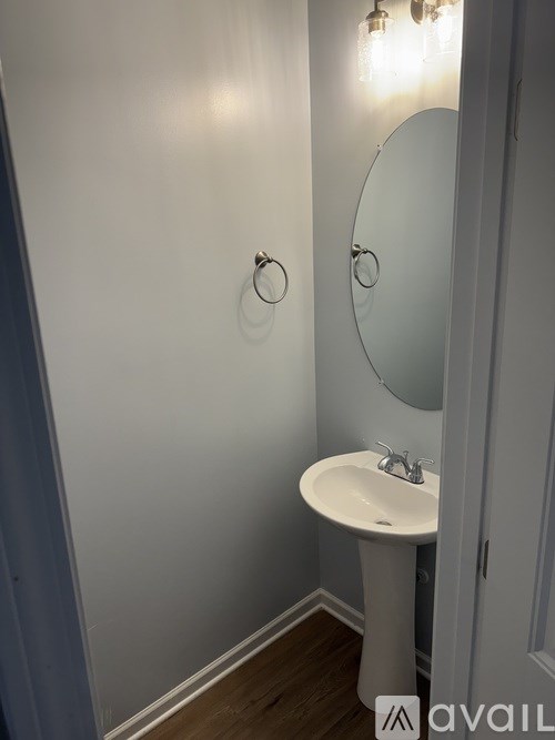 A white pedestal sink with a round mirror above it.