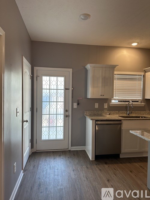 A kitchen with a white door and a window with a white frame.