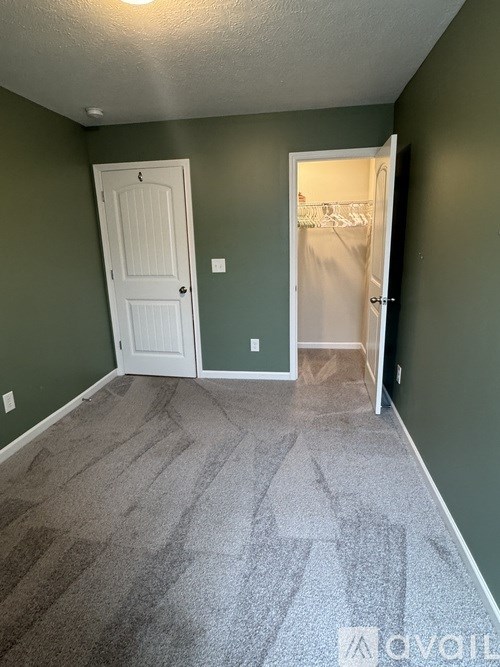 A room with a carpeted floor and two doors.