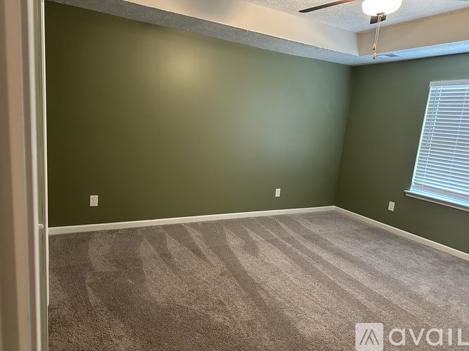 A room with a carpeted floor and a window with blinds.
