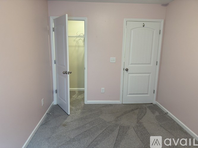 A room with a carpeted floor and two doors, one of which is open.