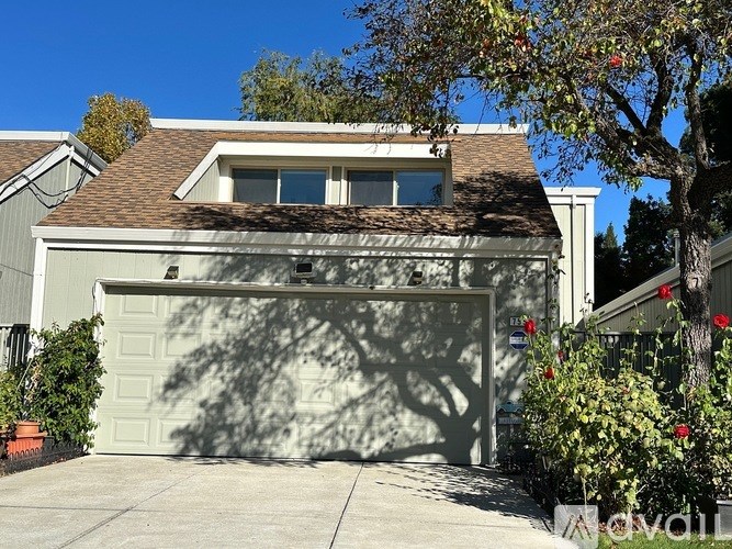 A tree in front of a house with a sign that says "avail".
