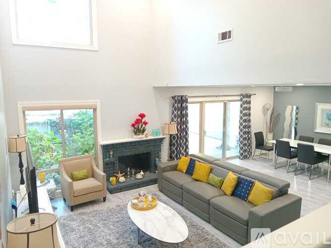 A living room with a grey couch and a fireplace.