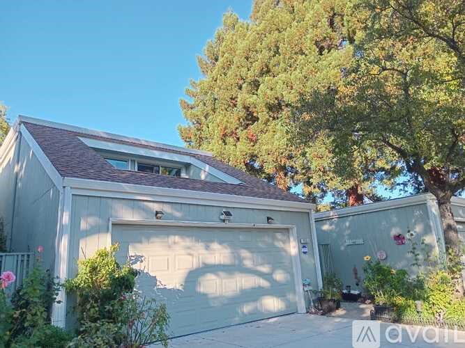 A house with a garage and a tree in front.