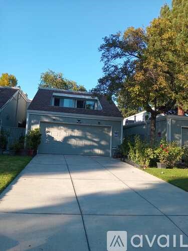 A house with a driveway and a tree in front of it.
