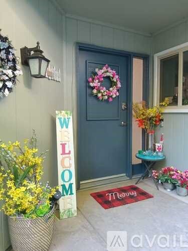 A blue door with a wreath and a sign that says "Welcome" on the porch.