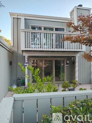 A white house with a balcony and a fence in front.