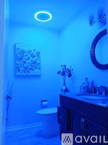 A bathroom with blue lighting and a white toilet.