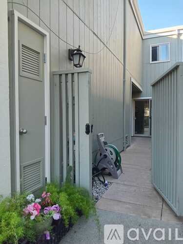 A grey building with a door and a lamp on the wall.