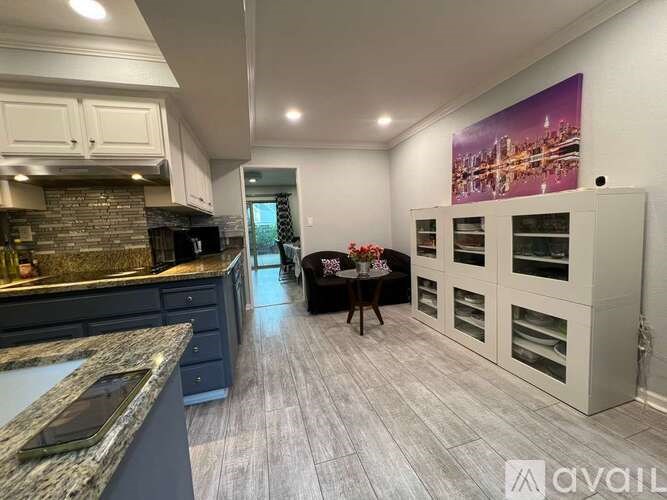 A modern kitchen with a dining area and a cityscape mural on the wall.