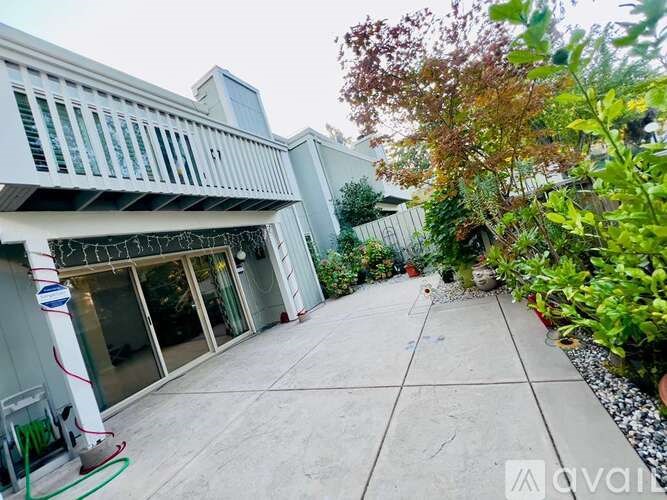 A patio area with a white building and a green hose.