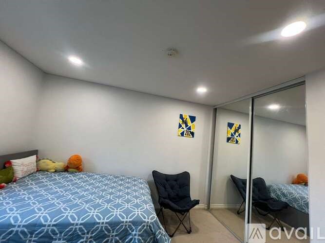 A bedroom with a blue bedspread and a black chair.