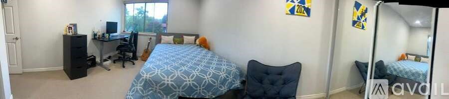 A bedroom with a bed, desk, and chair.