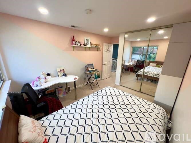 A bedroom with a bed, desk, and chair.