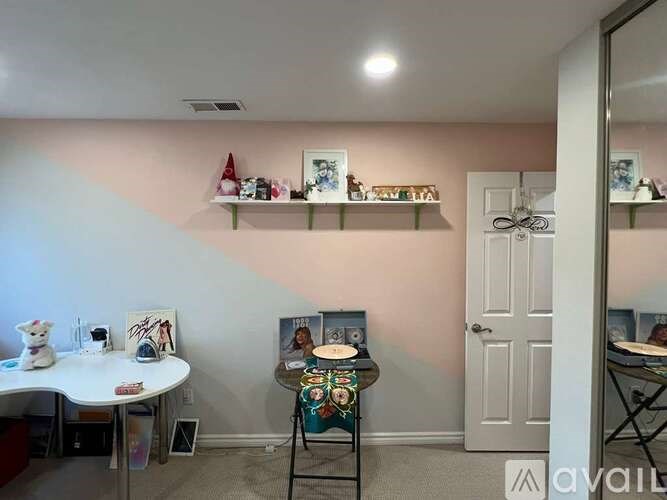 A room with a white table, a chair, and shelves with various items.
