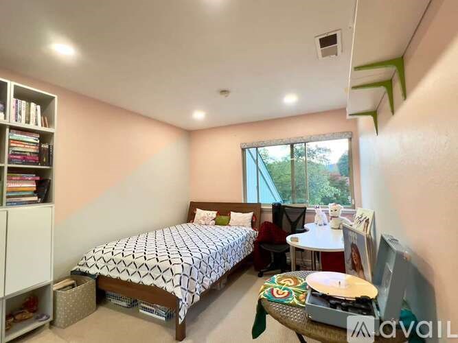 A bedroom with a bed, a chair, a table, and a window.