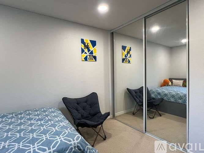 A bedroom with a bed, chair, and mirror.