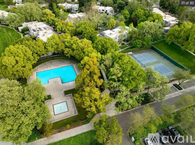 A bird's eye view of a residential area with a swimming pool surrounded by trees.