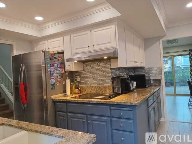 A kitchen with a granite countertop and a refrigerator covered in magnets.