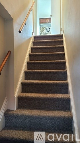 A staircase with a carpeted runner and wooden handrail.