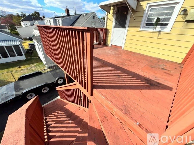 A wooden deck with a railing and steps leading to a house.