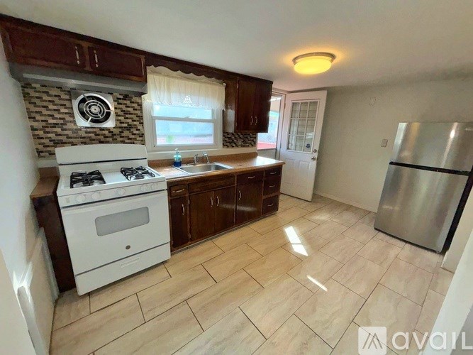 A kitchen with a stove, sink, and refrigerator.