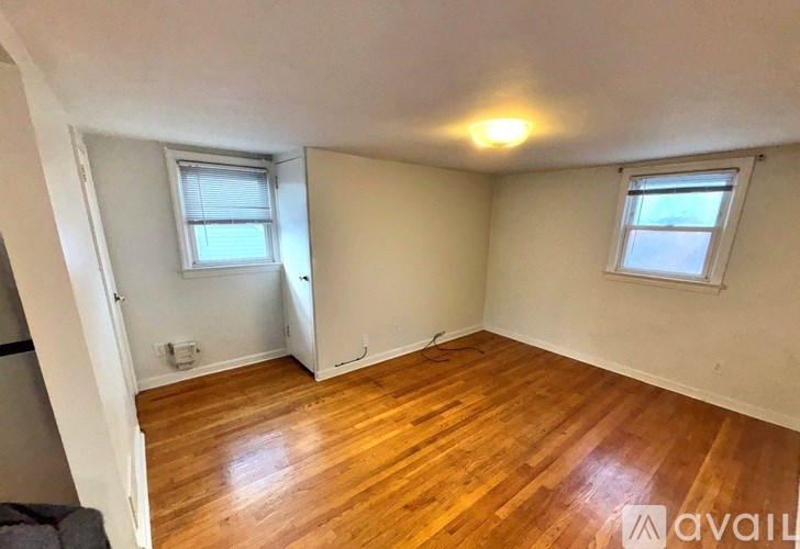 A room with wooden floors and two windows.