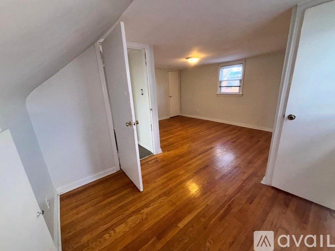 A room with wooden floors and white walls, with a window on the wall.