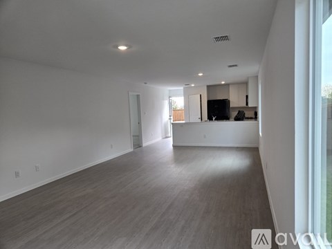 A spacious living room with a television and a kitchen area in the background.