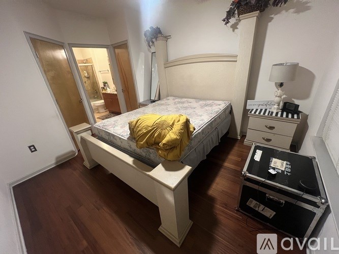 A bedroom with a bed, nightstand, and a suitcase on the floor.