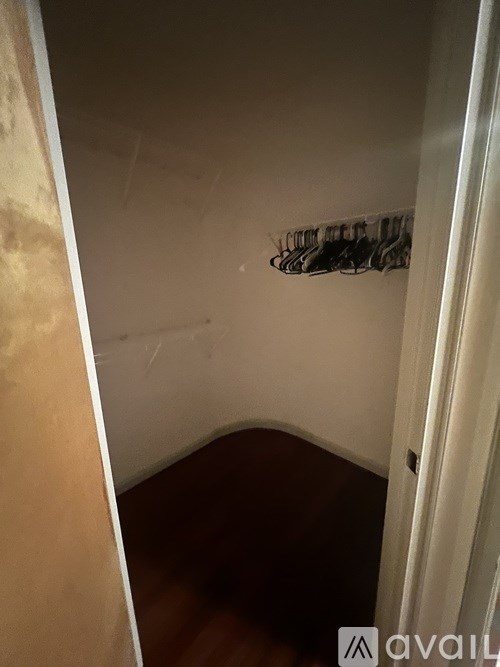 A small closet with a coat hanger on the wall.