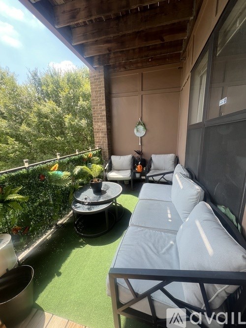 A balcony with a grey sofa, a table, and a hanging clock.