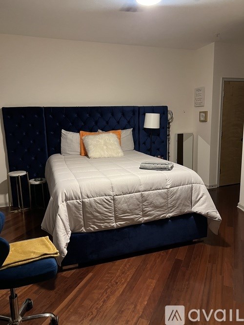 A bed with a white comforter and a blue headboard is in the image.