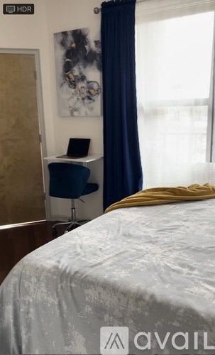 A bedroom with a bed, desk, chair, and a painting on the wall.