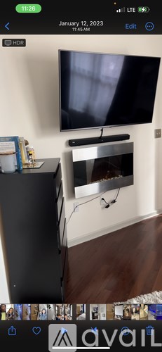 A black television is mounted on a wall above a black entertainment center.