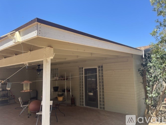 A patio area with a table and chairs under a roof.