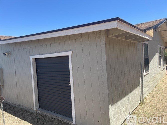 A small building with a grey roller shutter door and a white window.