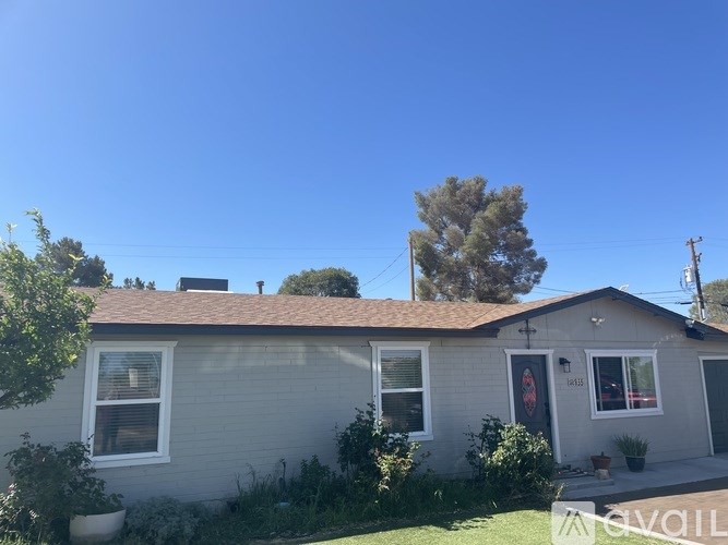 A house with a grey siding and a brown roof with a tree in the back.