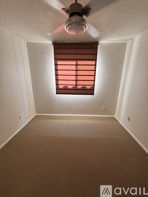 A room with a ceiling fan and a window with blinds.