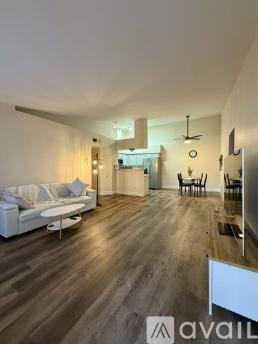 A living room with a white couch and wooden floors.