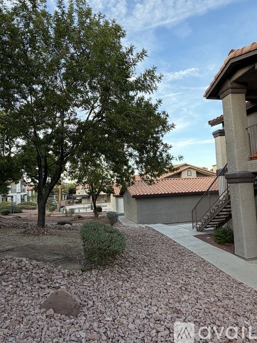 A residential area with a house, trees, and a gravel path.