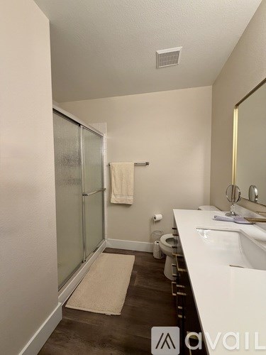 A bathroom with a white sink, mirror, and a beige rug.