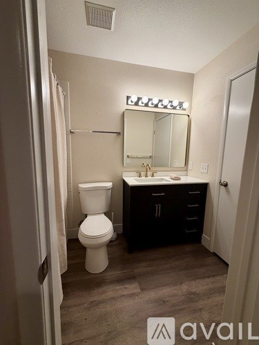 A bathroom with a toilet, sink, and mirror.