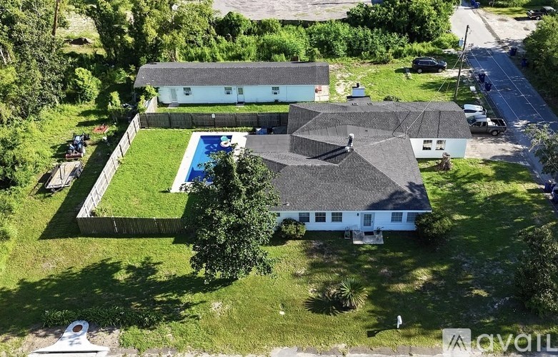 A large white house with a black roof and a pool in the backyard.