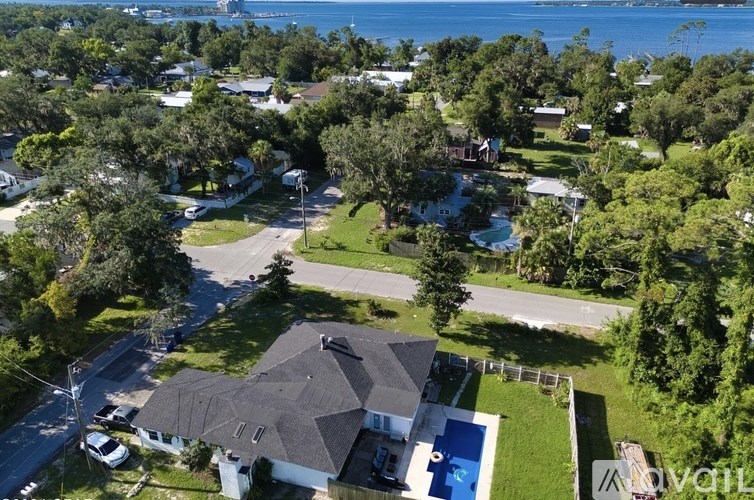A house with a pool is surrounded by trees and other houses.