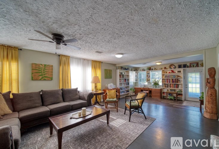 A living room with a grey sofa, a wooden coffee table, and a ceiling fan.
