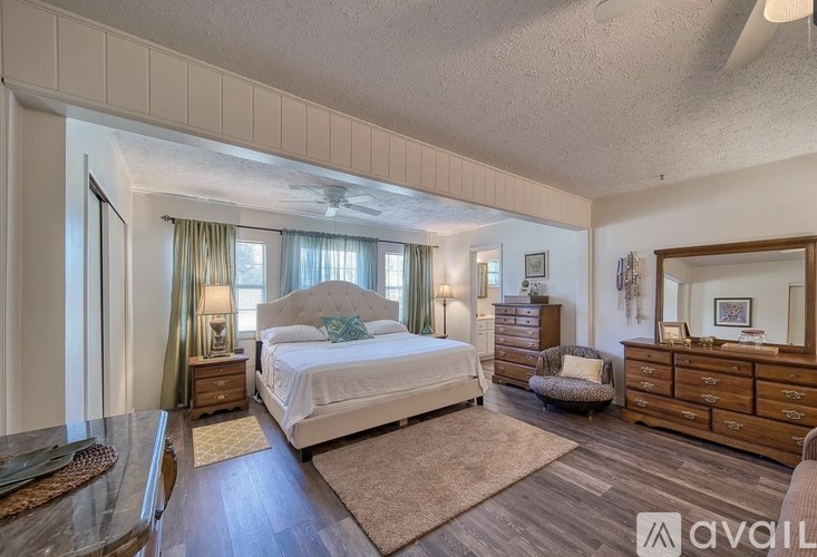 A bedroom with a large bed, a dresser, and a mirror.