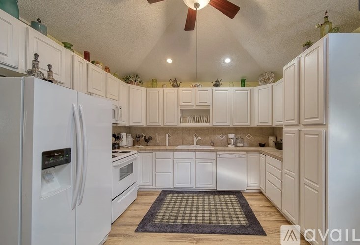 A kitchen with white appliances and cabinets.