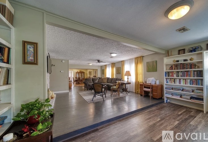 A living room with a couch, chairs, and a bookshelf.